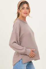 woman wearing a taupe long sleeve ribbed maternity top and gently holding her baby bump