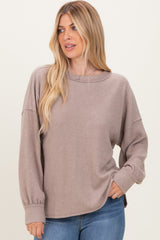 woman wearing a taupe ribbed long sleeve top with a relaxed fit and balloon sleeves paired with blue jeans