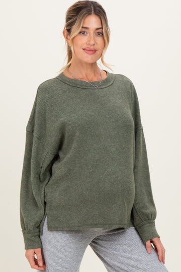 woman wearing a green oversized maternity sweater with long sleeves and a relaxed fit, showcasing her baby bump