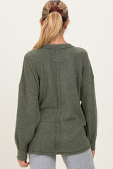woman wearing a green maternity sweater with a relaxed fit and dropped shoulders, seen from the back