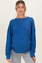 woman wearing a blue maternity sweater with a relaxed fit and wide sleeves, styled for comfort and versatility