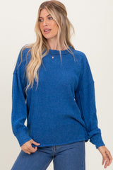 woman wearing a blue ribbed long sleeve top with a relaxed fit and rolled sleeves, paired with jeans