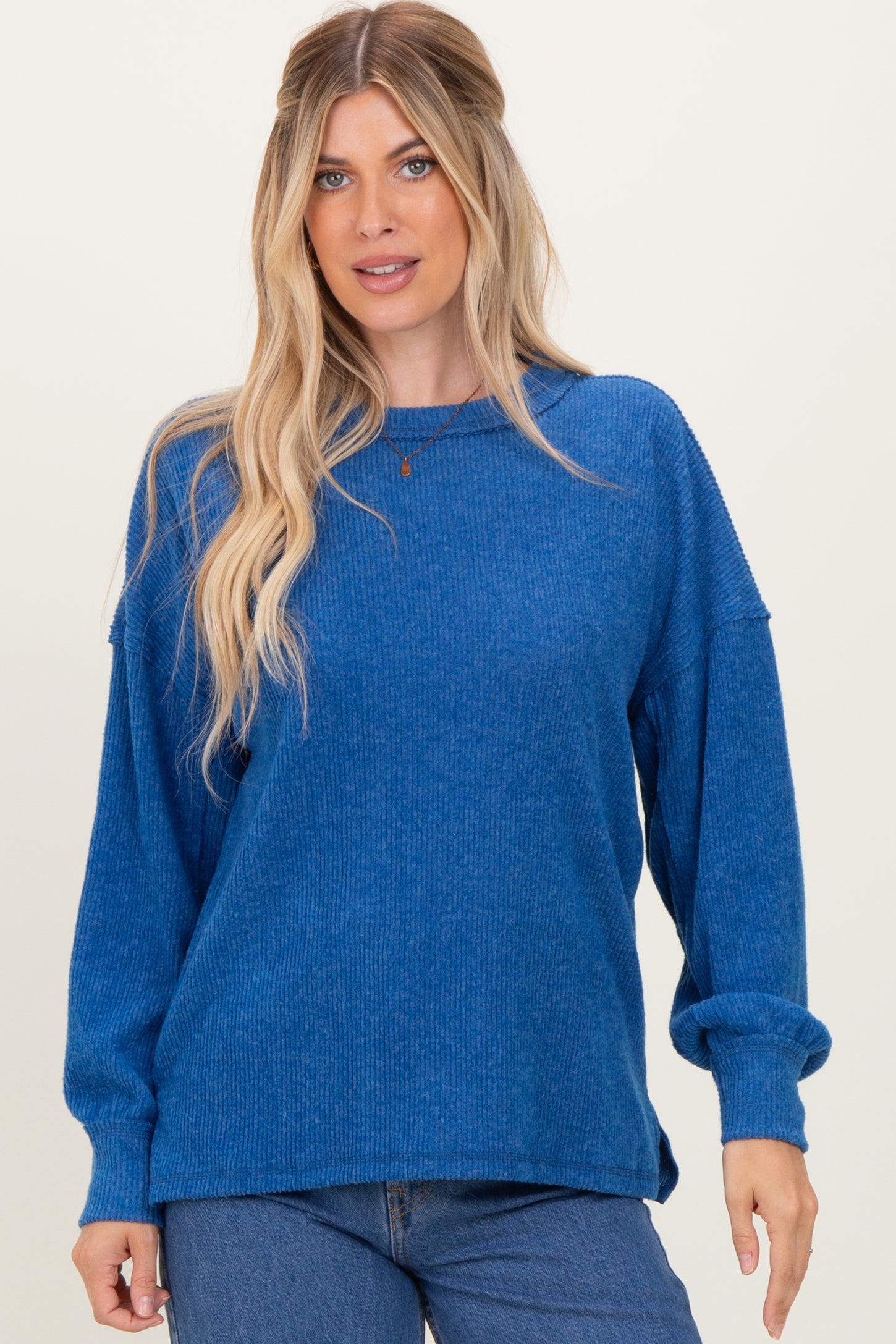 woman wearing a blue oversized ribbed sweater with long sleeves and a relaxed fit