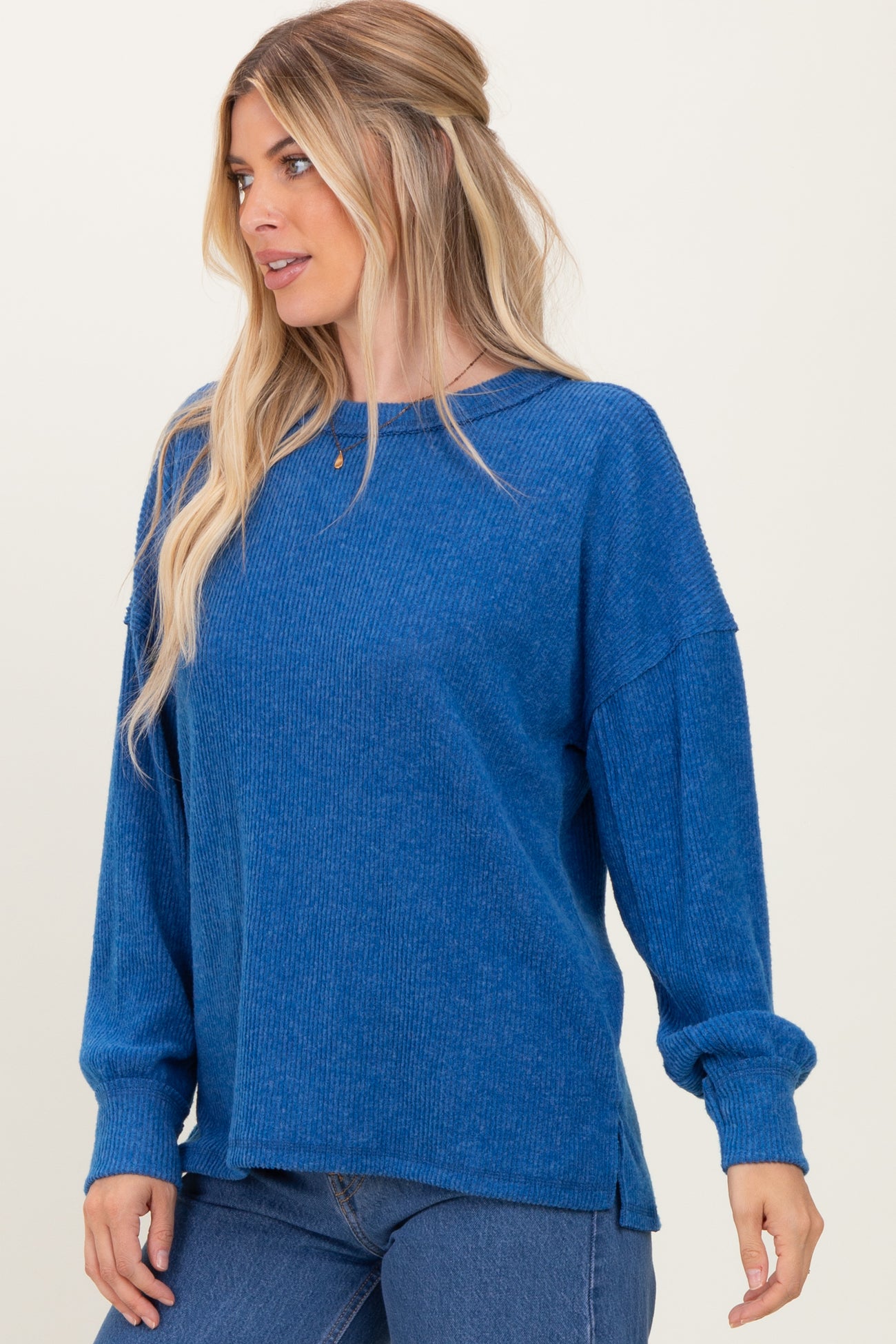 woman wearing a blue ribbed long sleeve sweater with a relaxed fit and side slits
