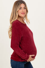 woman wearing a red ribbed long sleeve maternity sweater and holding her baby bump