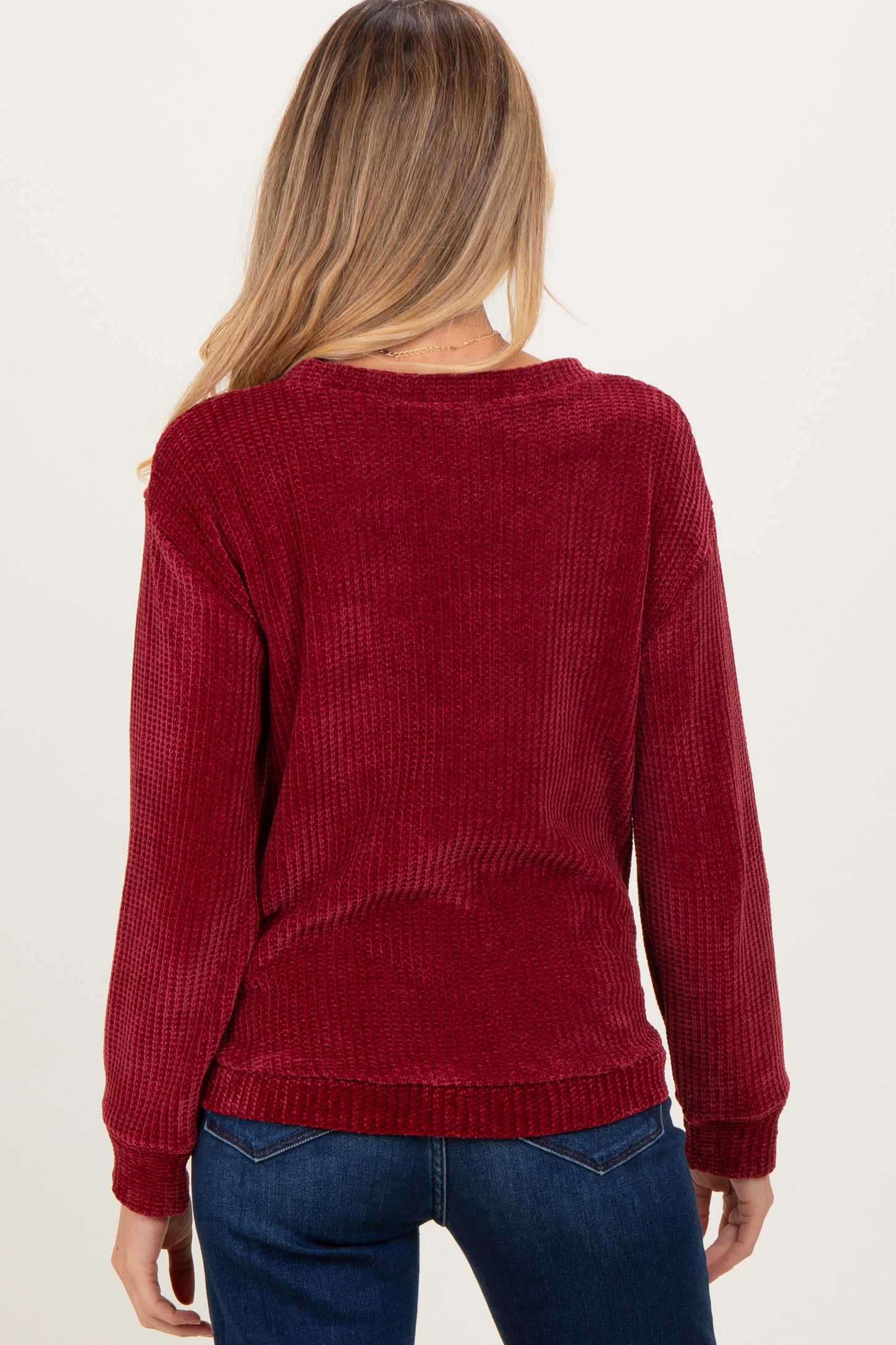 woman wearing a burgundy knit maternity sweater, facing away, showing loose fit and long sleeves