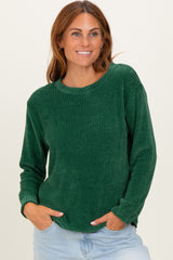 woman wearing a dark green ribbed long sleeve sweater with a relaxed fit and smiling at the camera