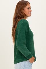 woman wearing a dark green ribbed long sleeve top, shown from the side with long hair cascading down