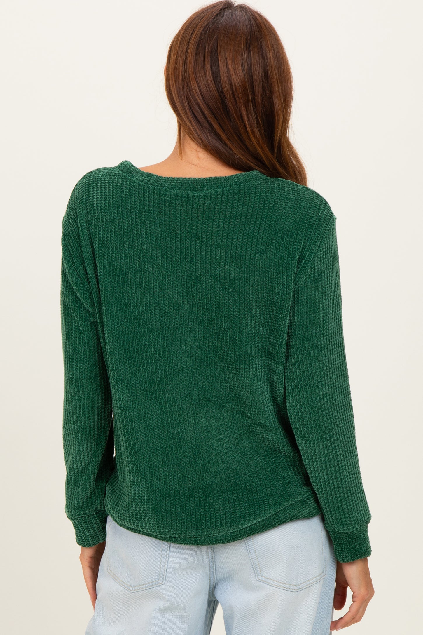 woman wearing a green ribbed long sleeve top, showing the back view with relaxed fit and soft texture