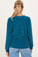 woman wearing a teal textured maternity sweater with long sleeves, shown from the back