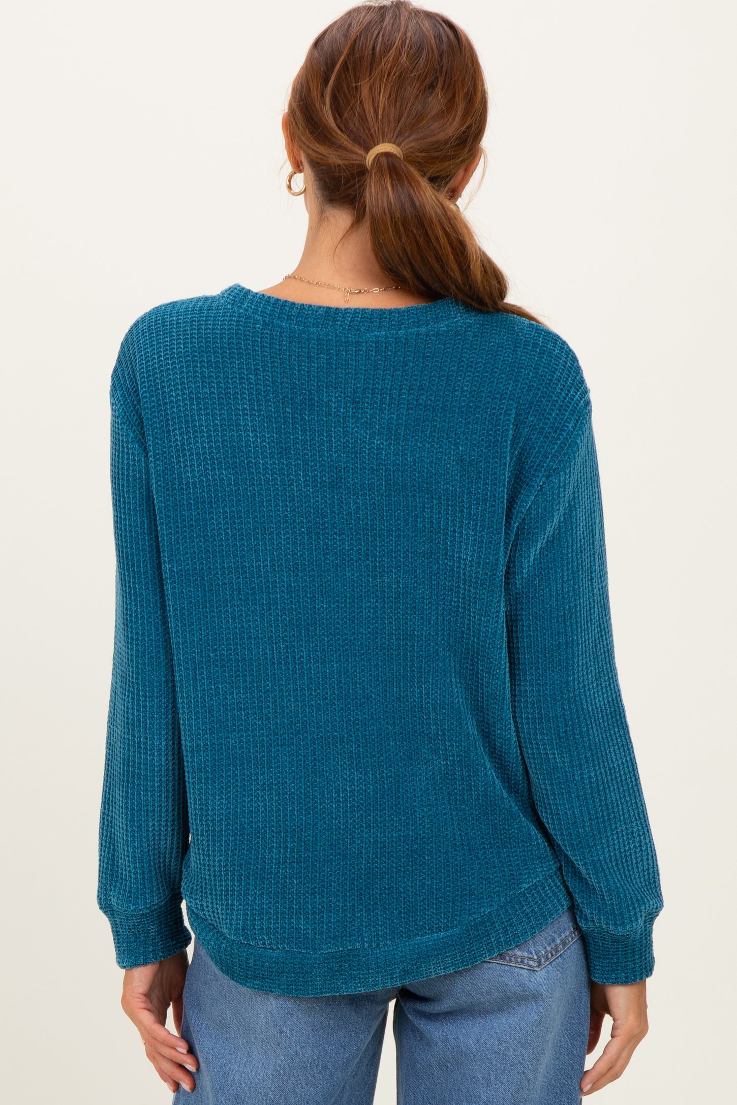 woman wearing a teal long sleeve waffle knit top, shown from the back, paired with light blue jeans