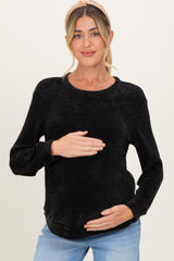 woman wearing a black ribbed maternity top and holding her baby bump