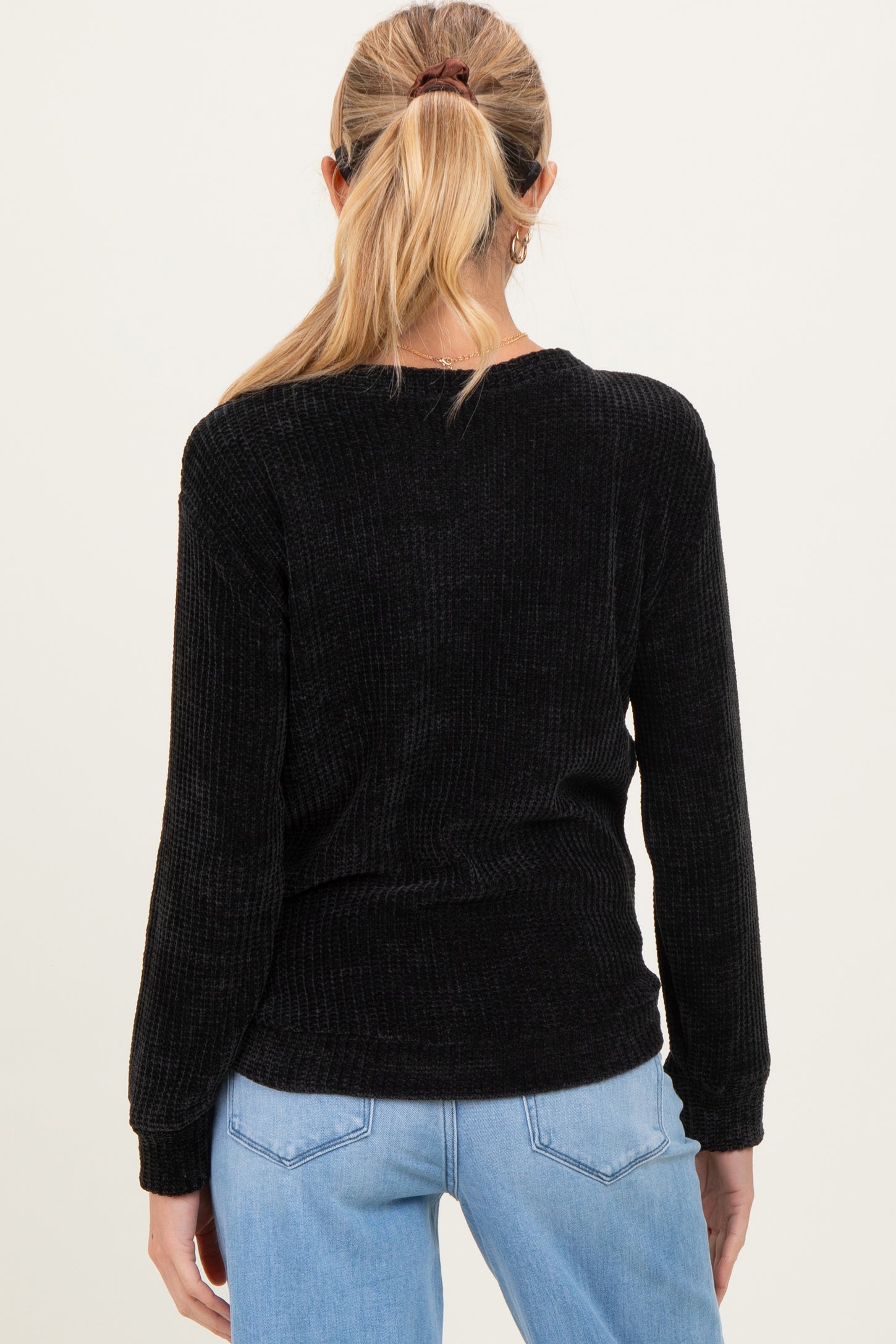 woman wearing a black ribbed maternity top with long sleeves, seen from the back