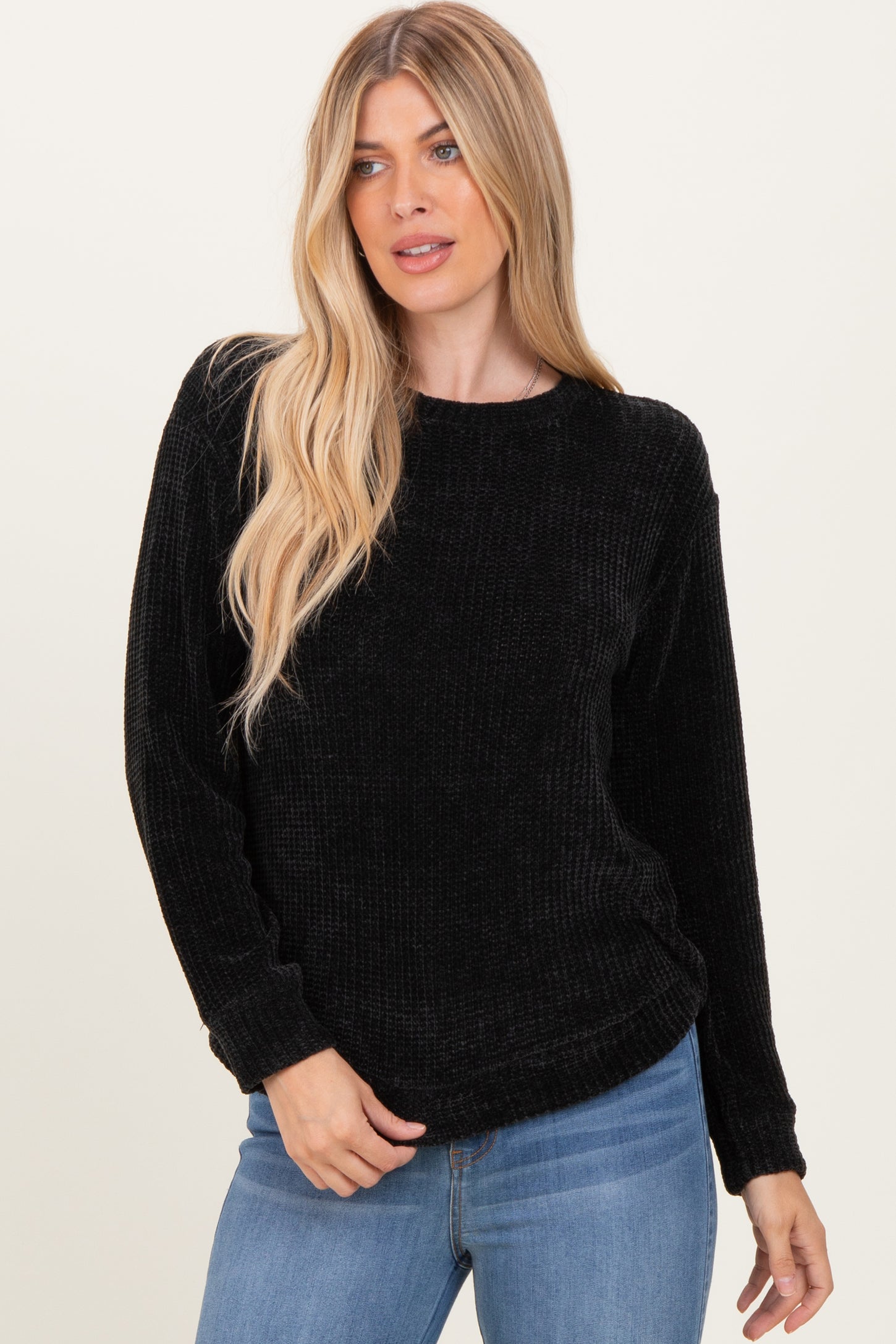 woman wearing a black ribbed long sleeve sweater and blue jeans