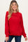 woman wearing a red textured maternity sweater with a relaxed fit and long sleeves, smiling at the camera
