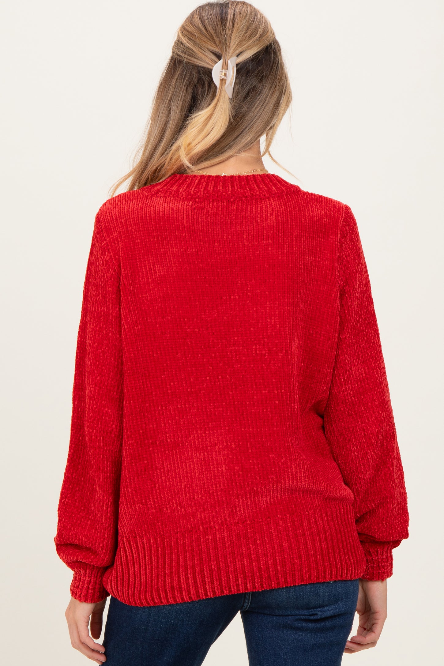 woman wearing a red maternity sweater with a textured finish and balloon sleeves, showing the back view