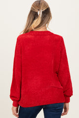 woman wearing a red maternity sweater with a textured finish and balloon sleeves, showing the back view