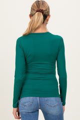 woman wearing a green long sleeve maternity top with a fitted style and ruching details at the back