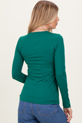 woman wearing a green long sleeve fitted top, showcasing the back view and styled with blue jeans