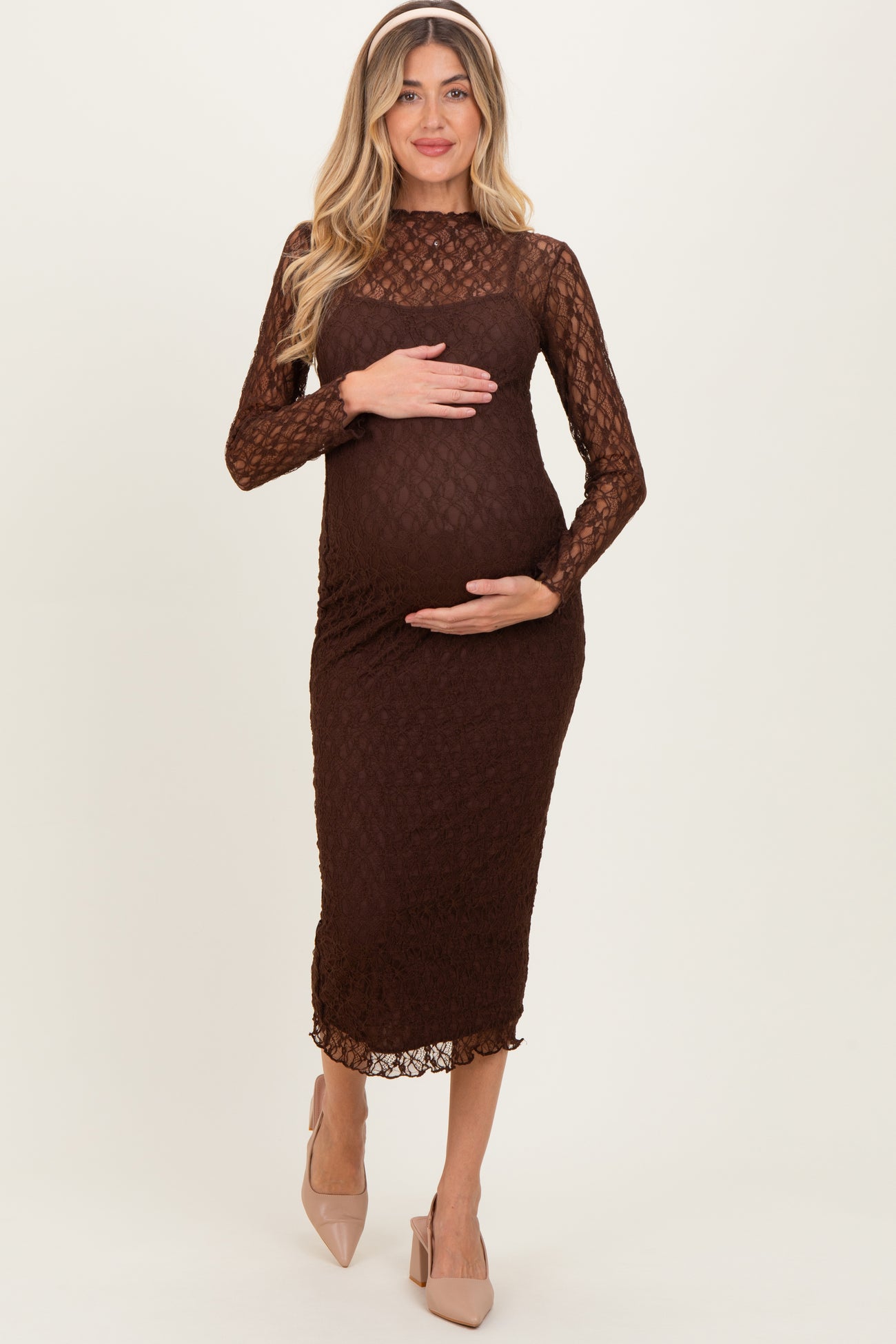 woman wearing a brown lace maternity dress and holding her baby bump