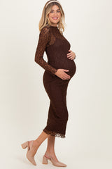 woman wearing a brown lace maternity dress with long sleeves and a fitted silhouette, holding her baby bump