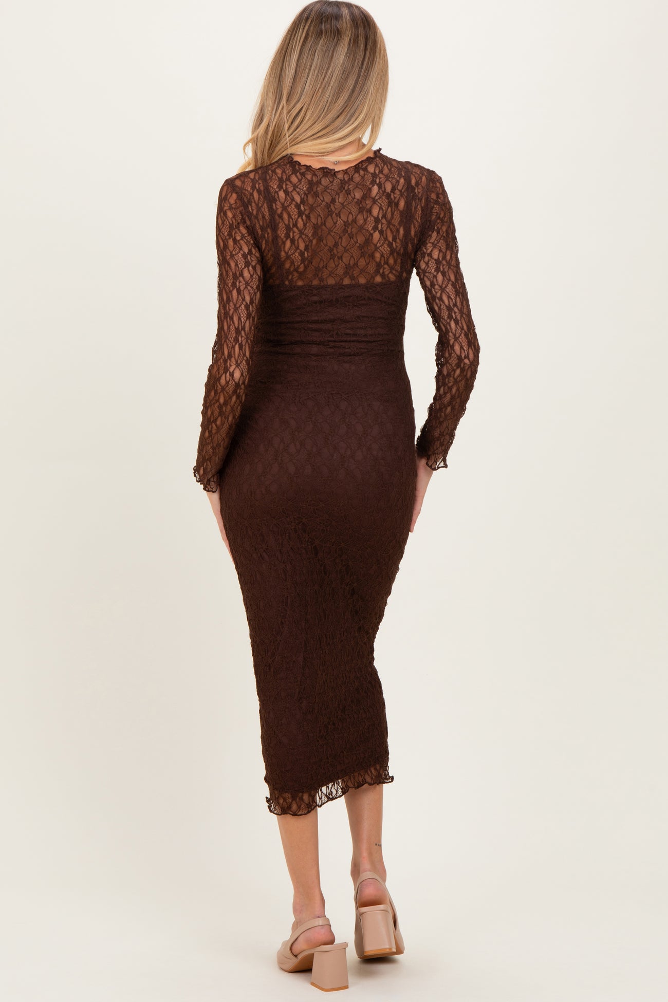 woman wearing a brown lace long sleeve maternity dress, showcasing a fitted silhouette and mid-length cut