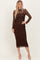 woman wearing a brown lace midi dress with long sleeves and a fitted silhouette, posing with one hand on her hip