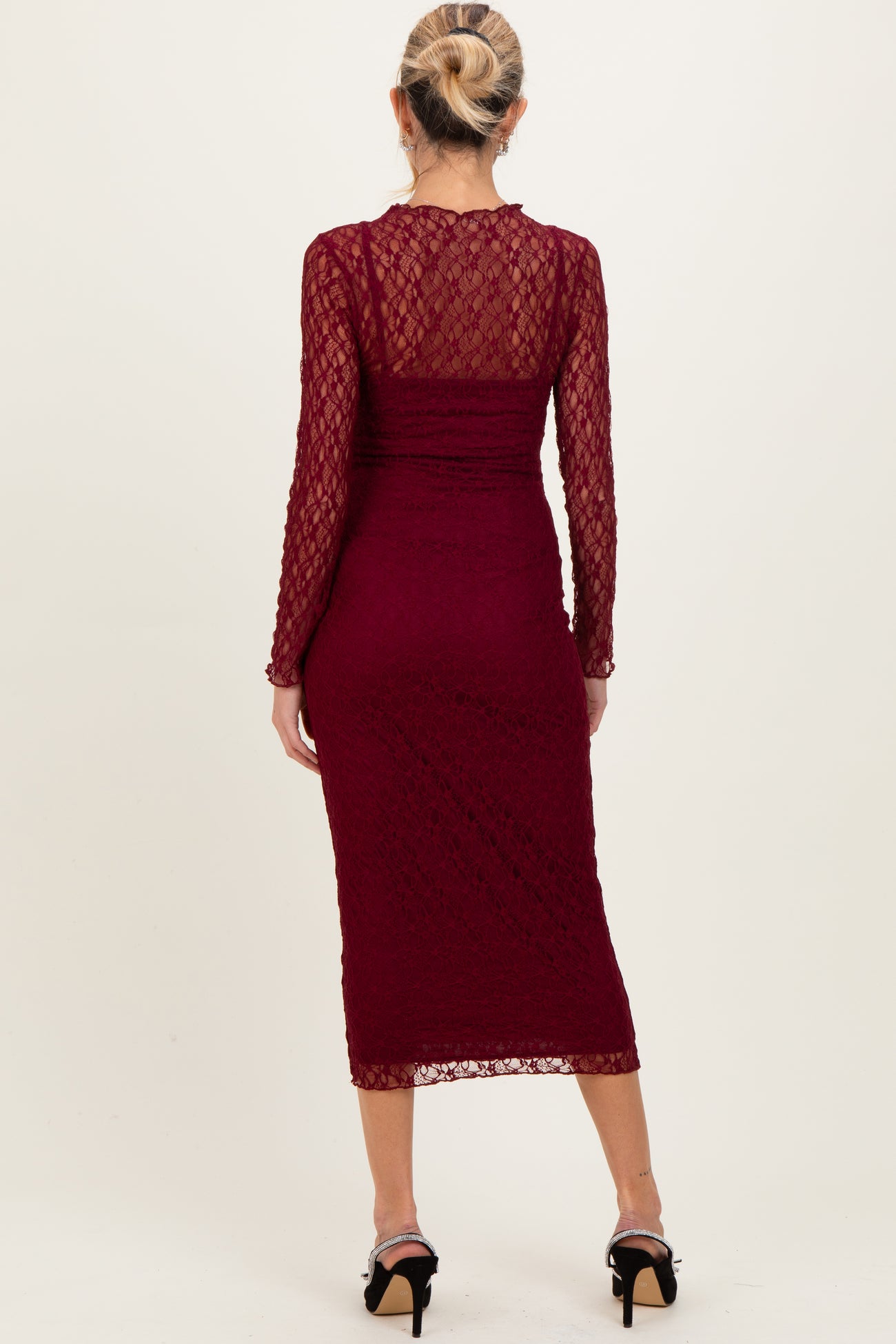 woman wearing a burgundy lace long sleeve maternity dress with a fitted silhouette and midi length