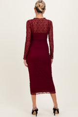 woman wearing a burgundy lace long sleeve maternity dress with a fitted silhouette and midi length