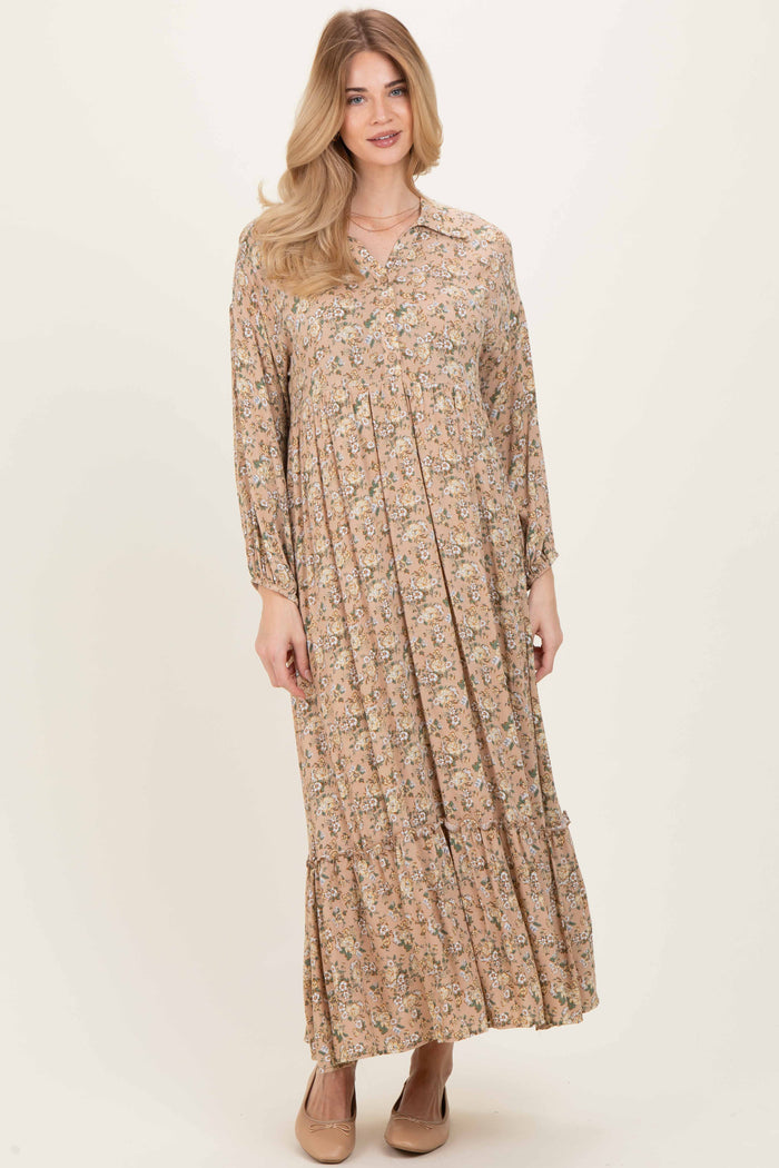 woman wearing a long-sleeve floral maxi dress in shades of beige and pink with a tiered skirt