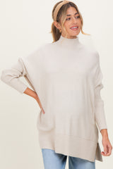 woman wearing a beige oversized turtleneck sweater, styled casually with light blue jeans