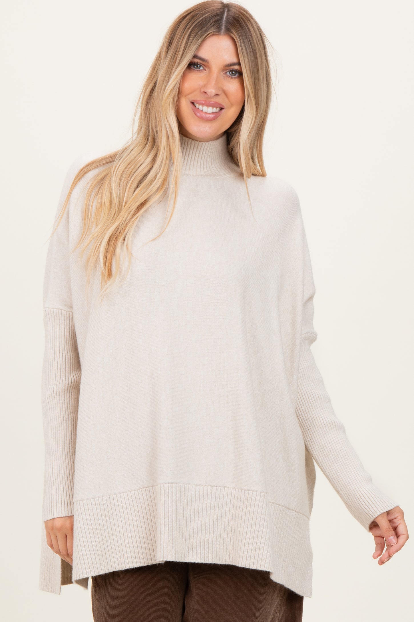 woman wearing a light beige oversized turtleneck sweater with ribbed details and a relaxed fit