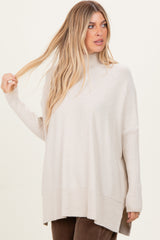 woman wearing a beige oversized turtleneck sweater with ribbed details and side slits