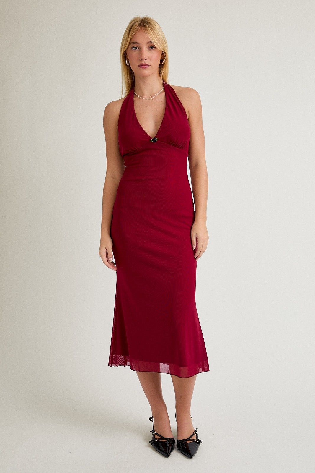 woman wearing a burgundy halter neck midi dress with a fitted silhouette and a flowy hemline