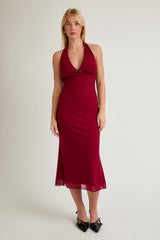 woman wearing a burgundy halter neck midi dress with a fitted silhouette and a flowy hemline