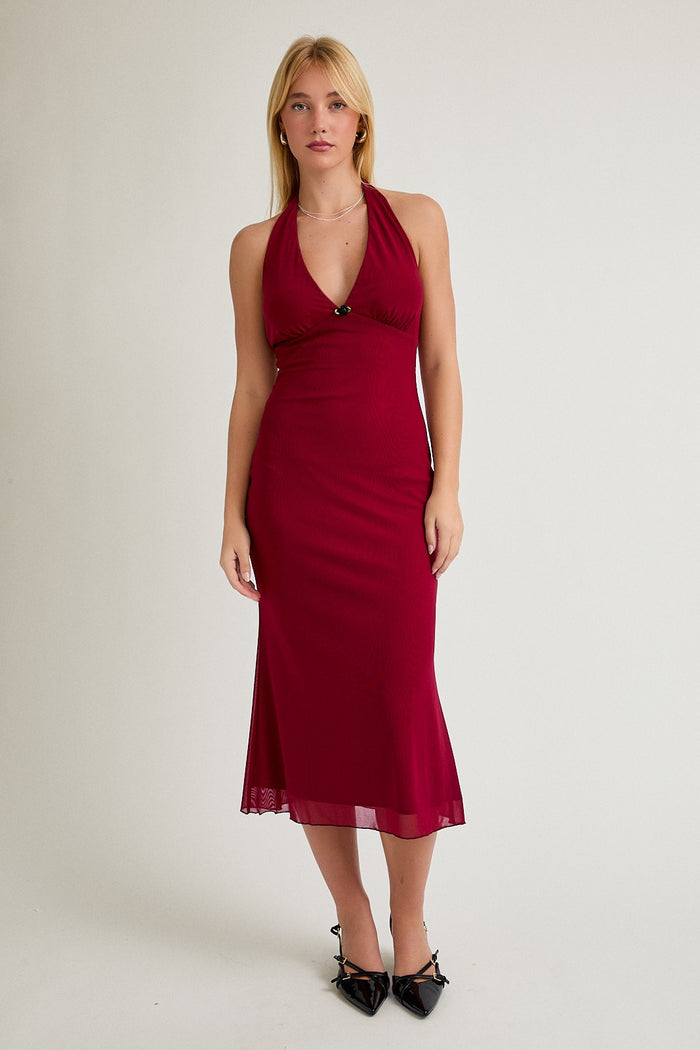 woman wearing a burgundy halter neck midi dress with a fitted silhouette and a flowy hemline