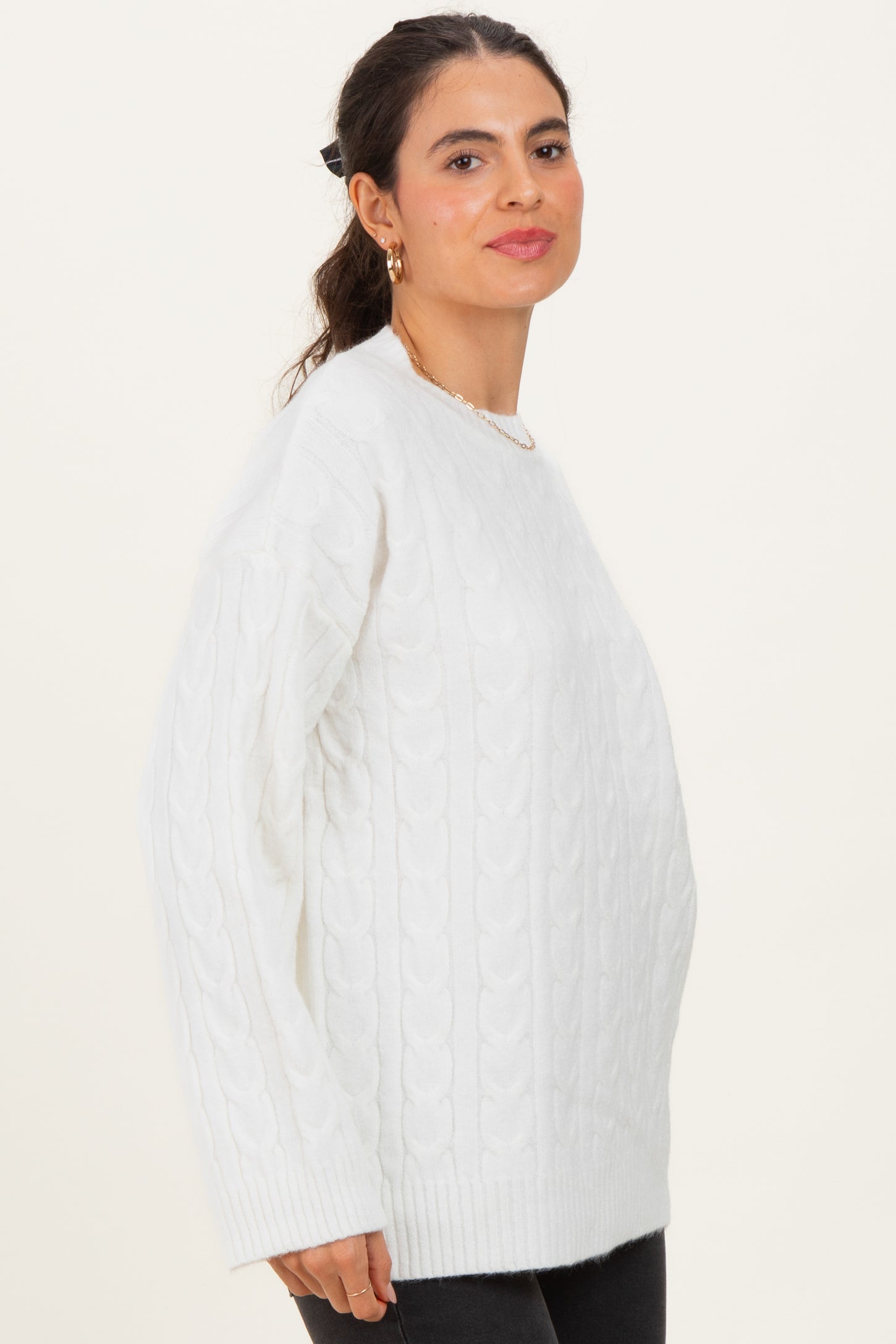 woman wearing a white cable knit sweater with long sleeves and a relaxed fit