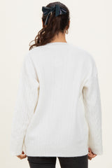 woman wearing a white cable knit sweater with a relaxed fit and long sleeves, shown from the back