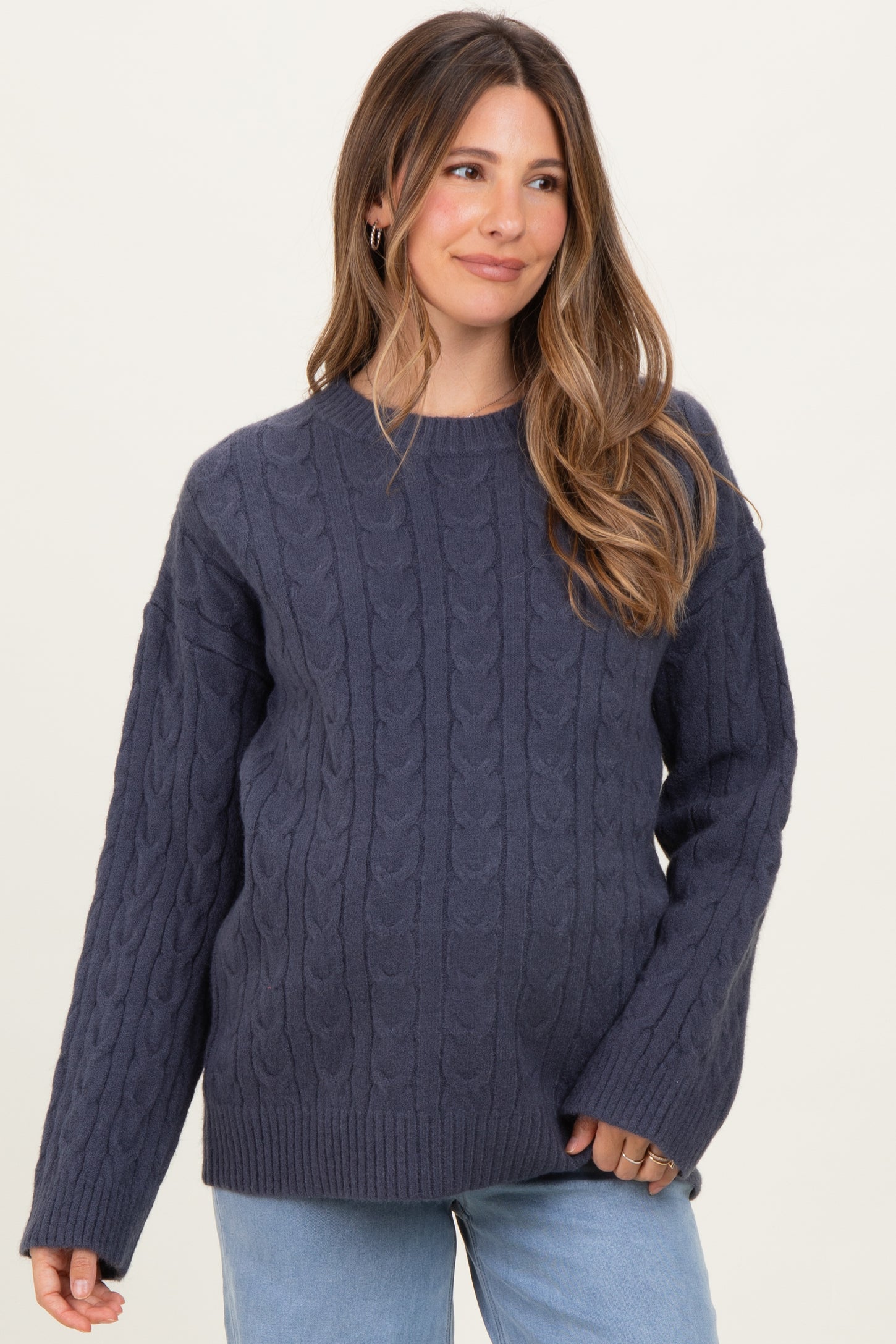woman wearing a dark navy chunky knit maternity sweater with a relaxed fit and cable knit design