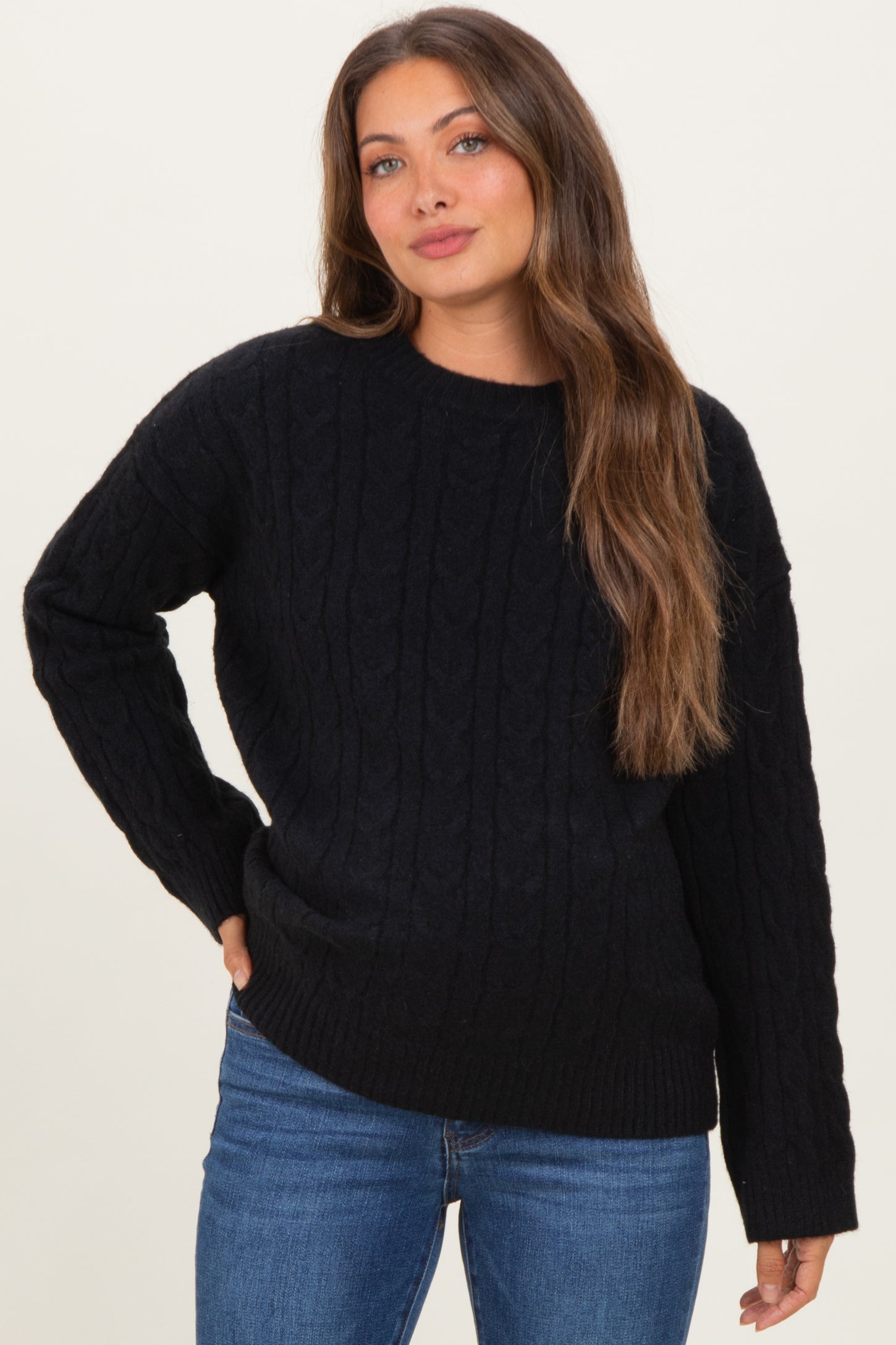 woman wearing a black cable knit maternity sweater with long sleeves and relaxed fit