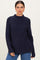 woman wearing a dark navy ribbed knit sweater with a high neckline and relaxed fit, paired with blue jeans