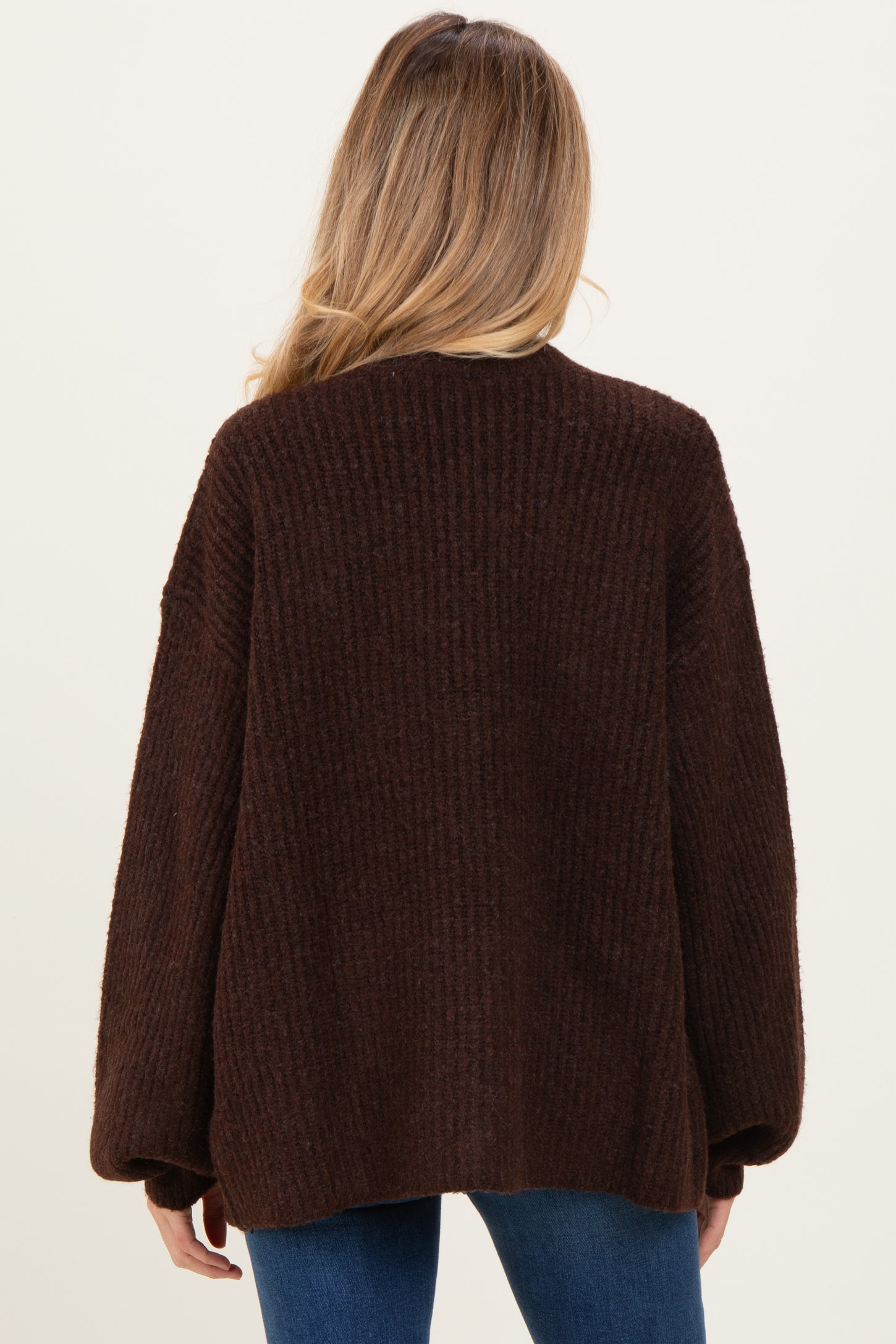 woman wearing a brown oversized knitted maternity cardigan, showing the back view