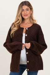 woman wearing a brown maternity cardigan with oversized sleeves and buttons, showcasing her baby bump