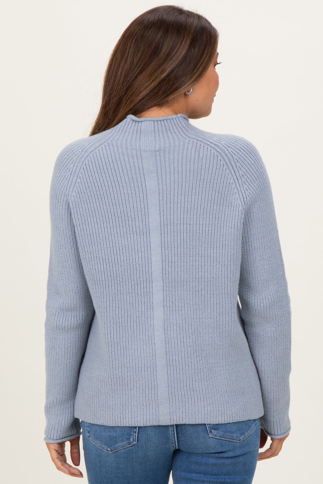 woman wearing a light blue maternity sweater with ribbed texture and fitted sleeves, seen from the back