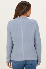 woman wearing a light blue maternity sweater with ribbed texture and fitted sleeves, seen from the back