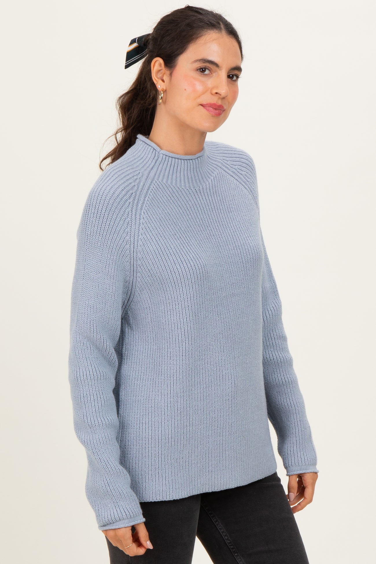 woman wearing a light blue ribbed long sleeve sweater with a round neck and relaxed fit