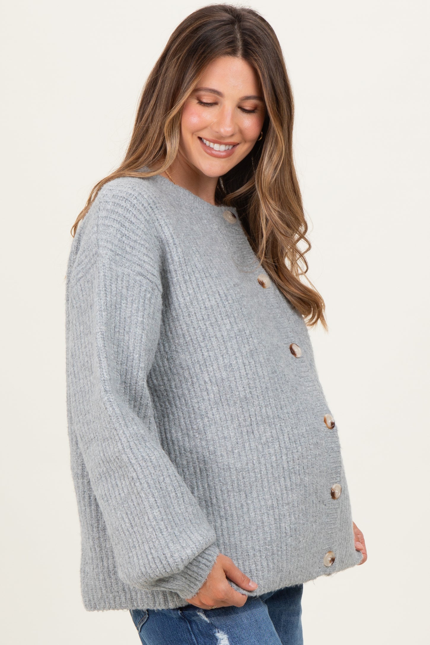 woman wearing a gray ribbed maternity cardigan with buttons and a visible baby bump