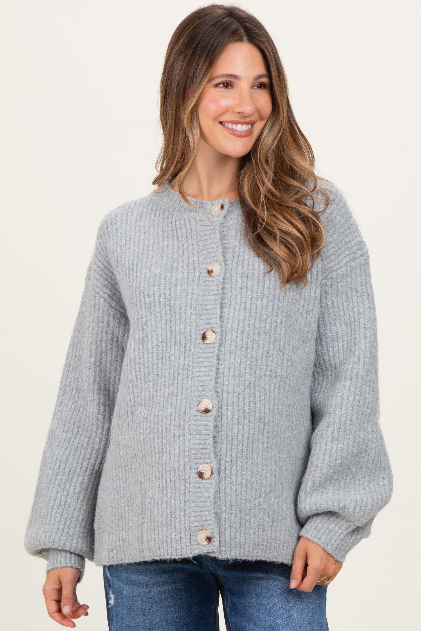 woman wearing a light gray oversized button-up maternity sweater with balloon sleeves and a round neckline