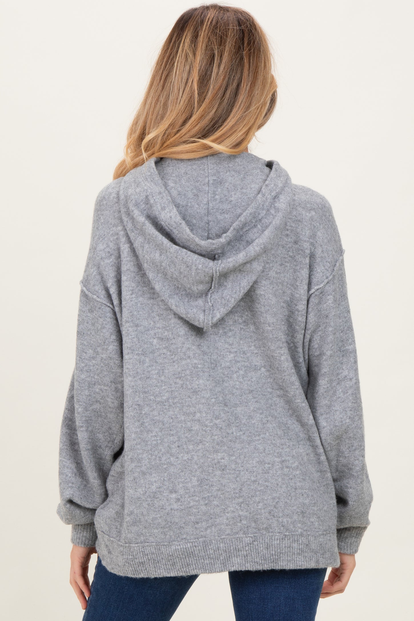 woman wearing a cozy grey maternity hoodie with a relaxed fit and a hood, showing the back view