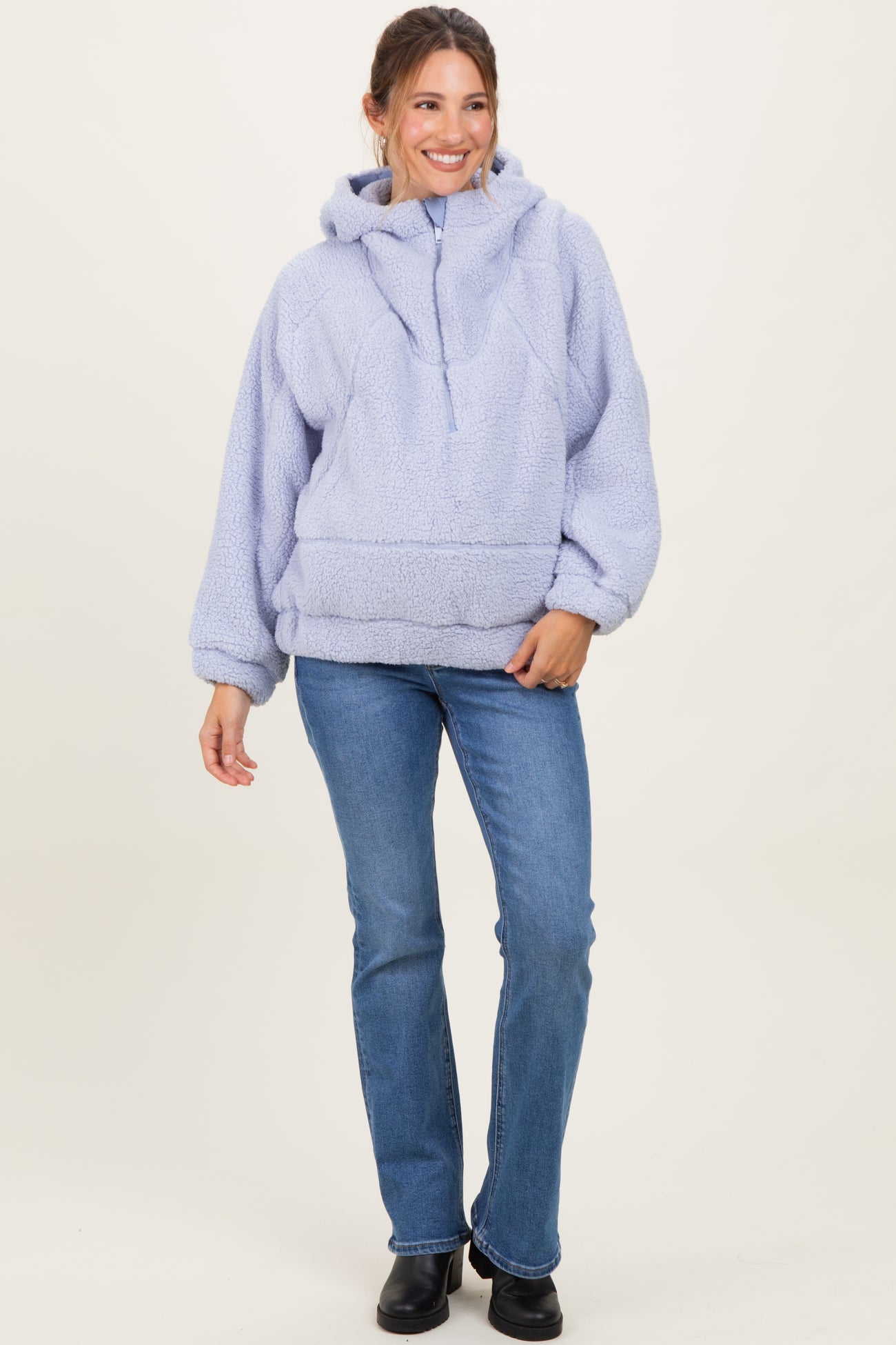 woman wearing a light lavender oversized maternity pullover hoodie with a front pocket and hood, paired with blue jeans